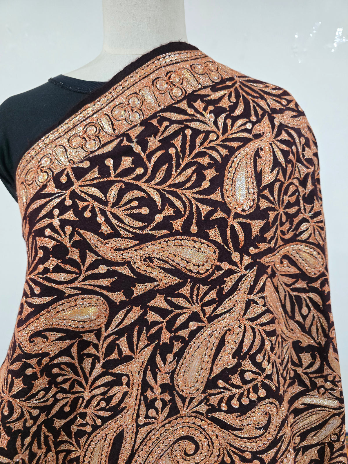 Close-up of the shawl shoulder with outlined paisleys, small leaves and a row of circular motifs along the border.