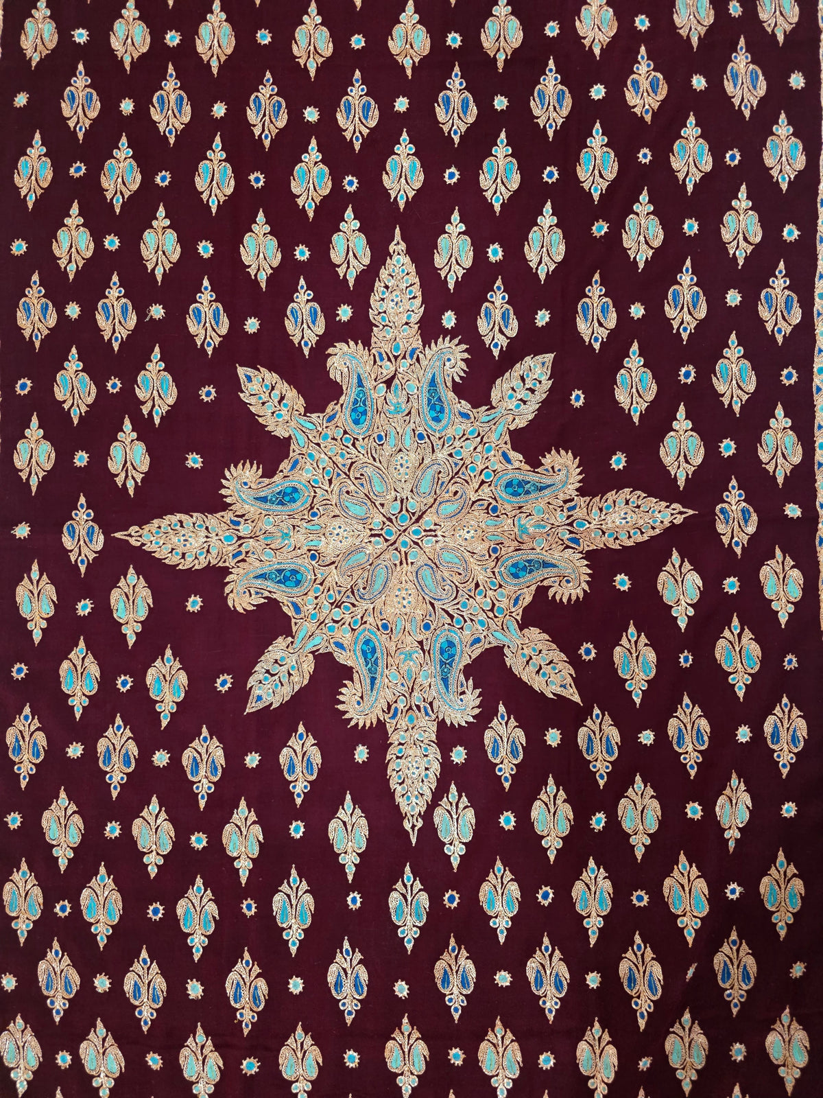 Flat view of garnet Pashmina shawl showing a central gold medallion surrounded by rows of turquoise and blue-accented motifs