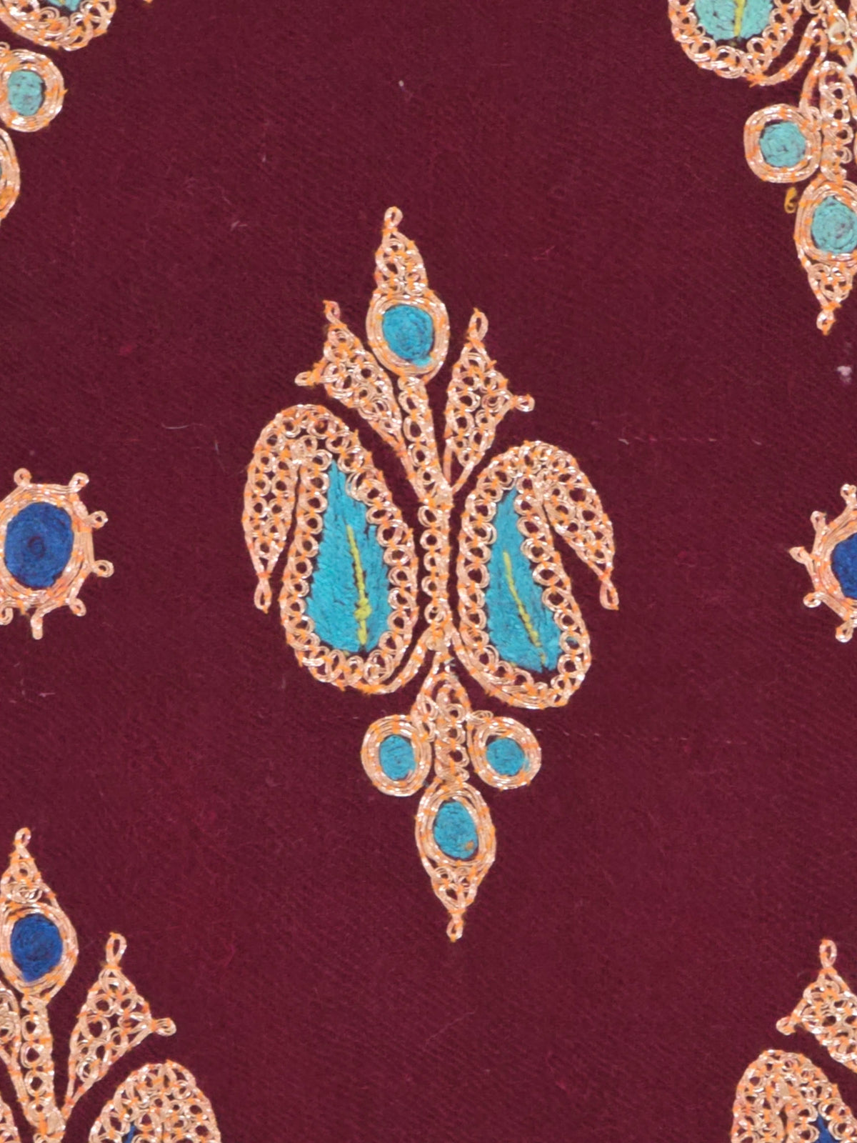 Close-up of a gold embroidered motif with turquoise centres surrounded by small blue accents on garnet Pashmina shawl