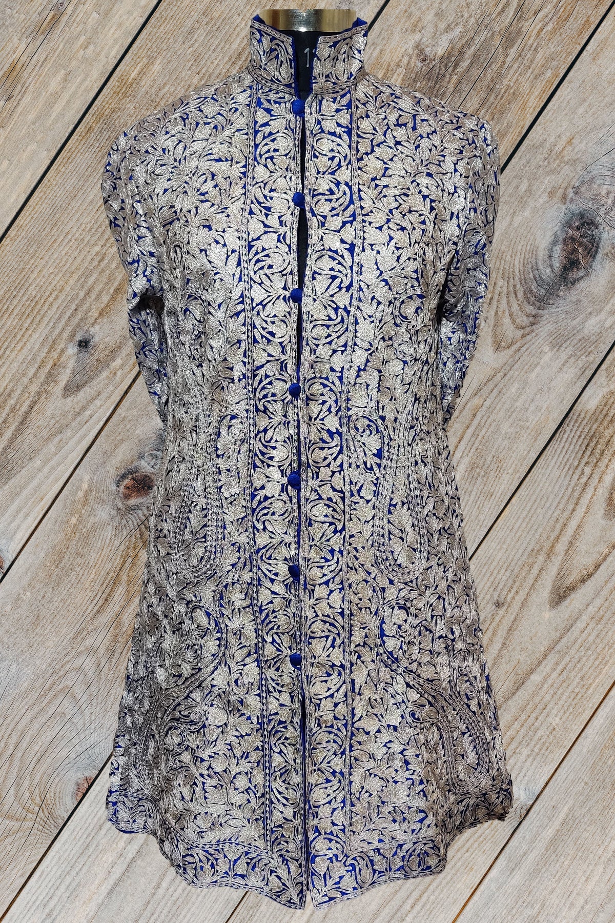 Front of the deep blue jacket with silver-toned Aari floral embroidery, covered blue buttons and narrow flower borders.