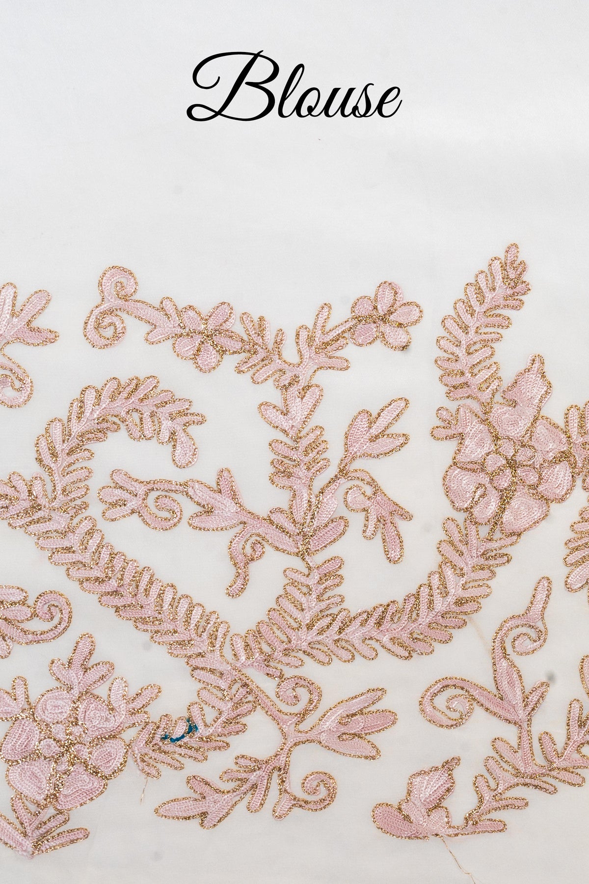 White blouse fabric with pale beige-pink Aari flowers and leafy scrolls outlined in gold Zari, labelled Blouse