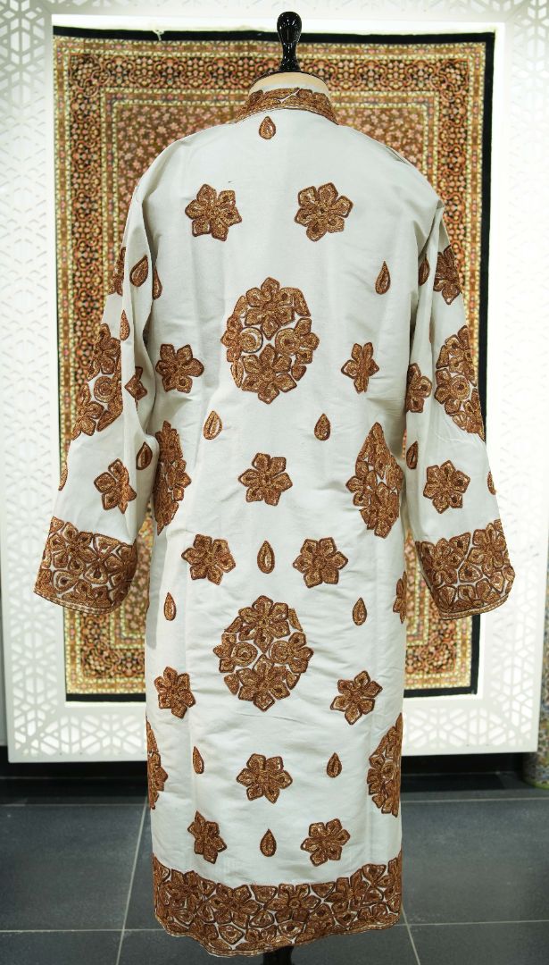 Full back of an ivory jacket with copper-brown floral medallions, small flowers and teardrop motifs above an embroidered hem.