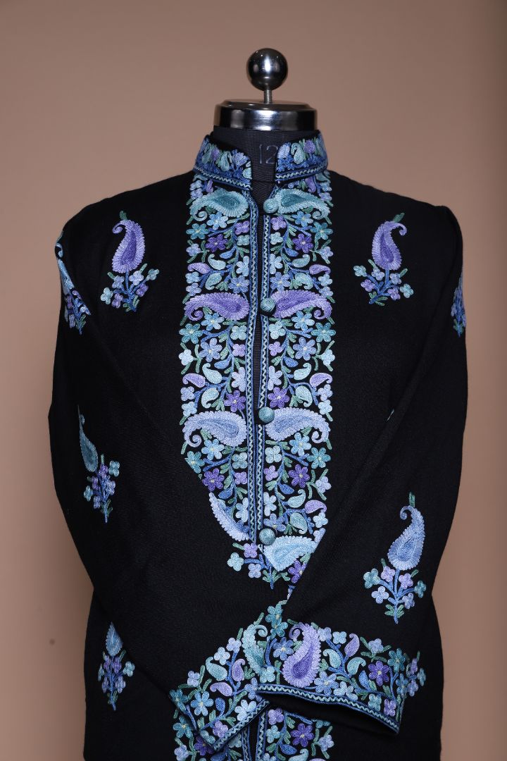 Upper front of the black jacket with crossed sleeves, pale blue and purple paisleys, and dense floral embroidery along the opening.
