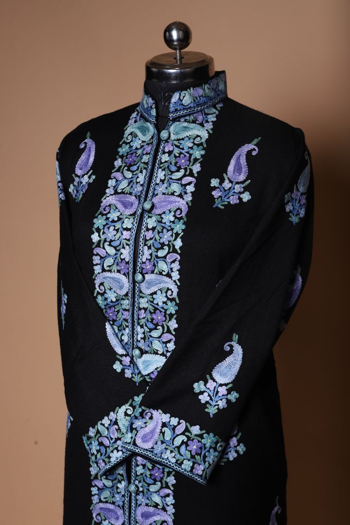 Angled upper-front view of the black jacket, showing the high collar and blue-purple embroidered paisleys around the buttoned opening.