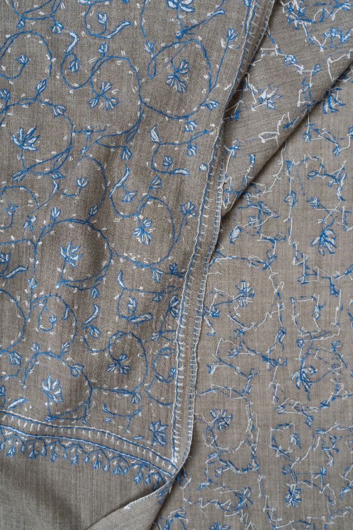 Folded grey shawl corner showing the front and reverse of blue and pale Sozni floral embroidery