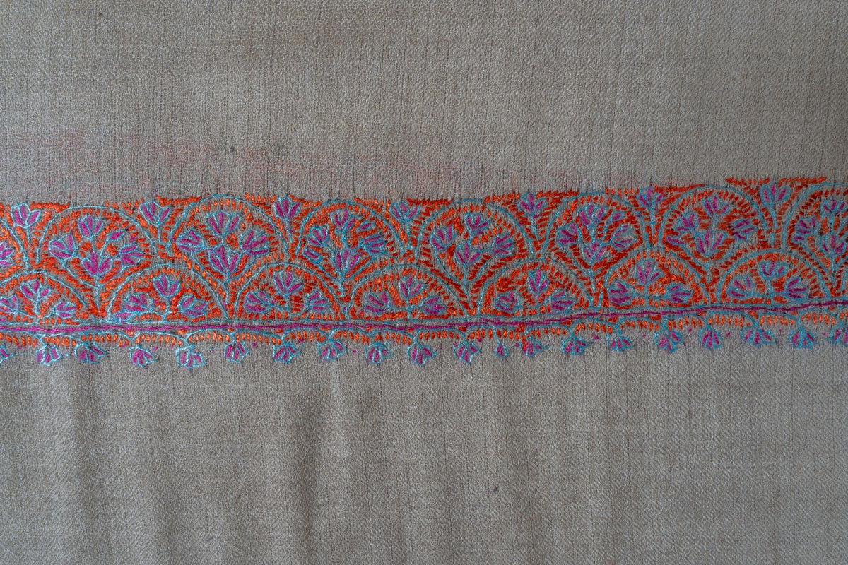 Close-up of red, turquoise and violet floral stitching in the beige shawl’s narrow end border