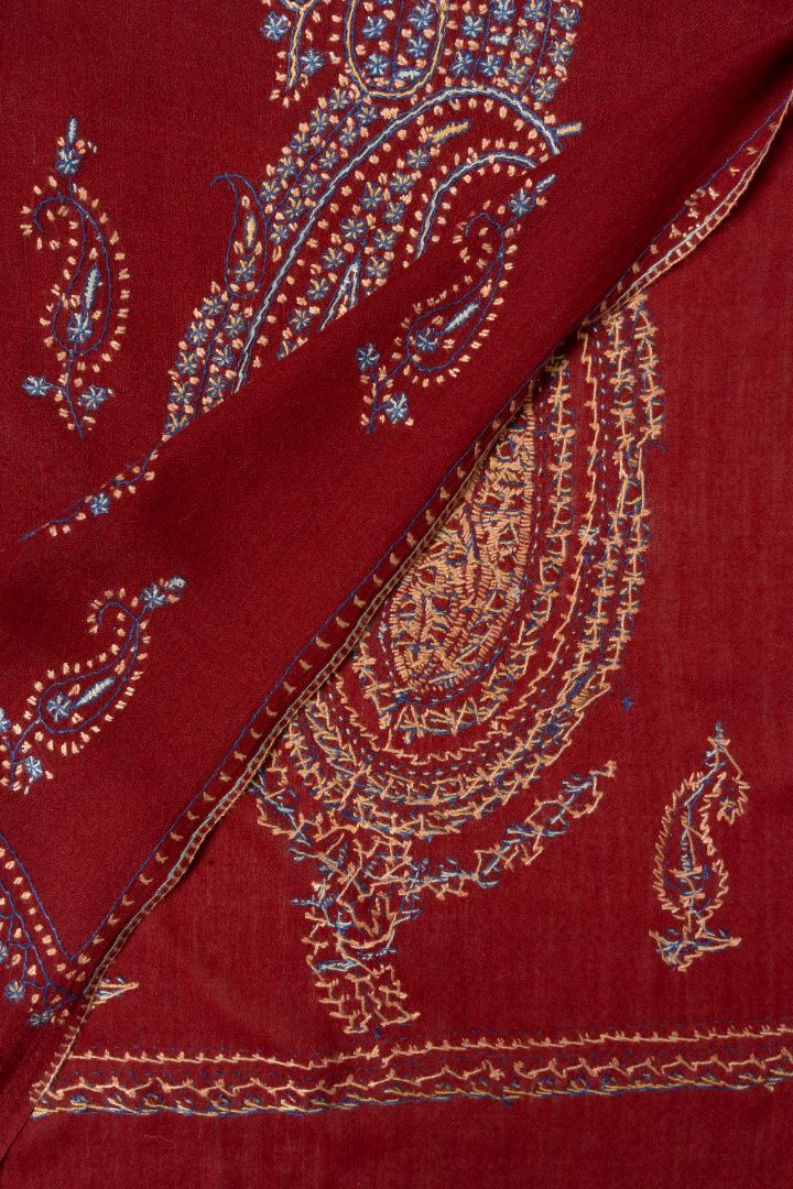 Folded deep red shawl corner showing the front and reverse of multicoloured Sozni paisley stitching