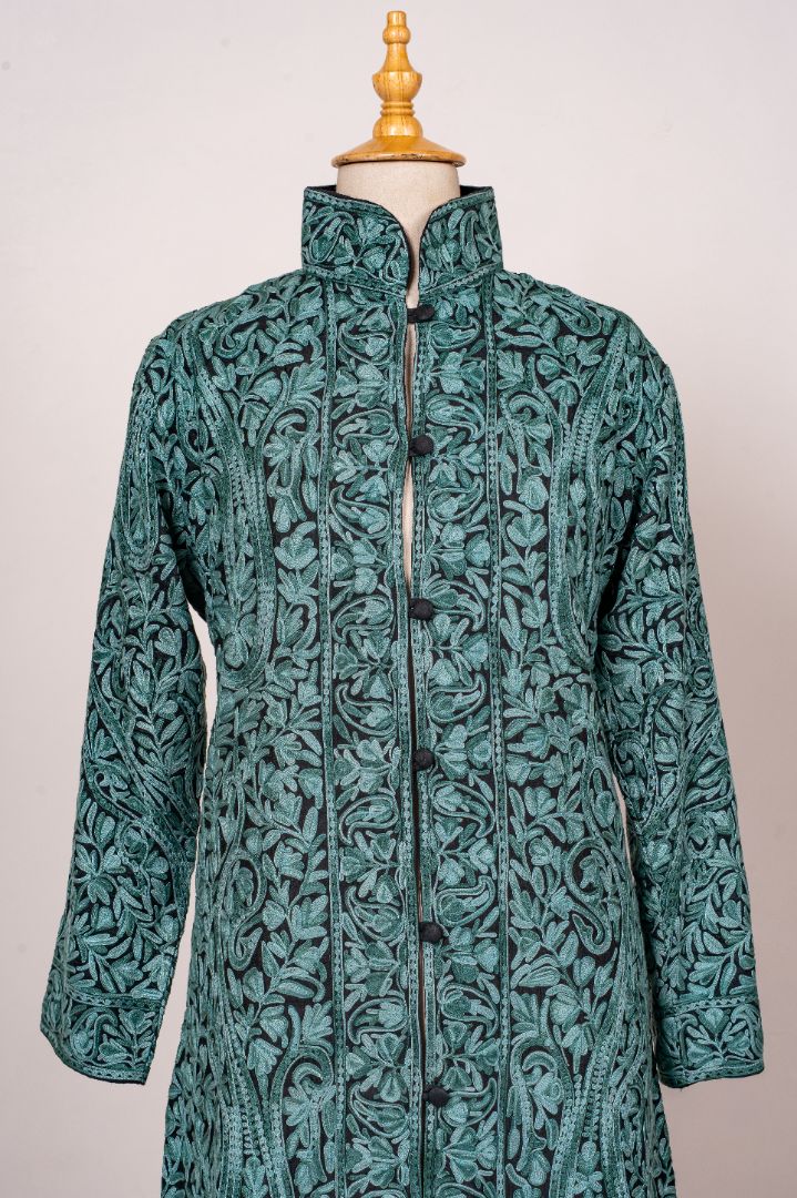 Front detail of a teal jacket with dense turquoise Aari foliage, a tall stand collar and dark covered buttons
