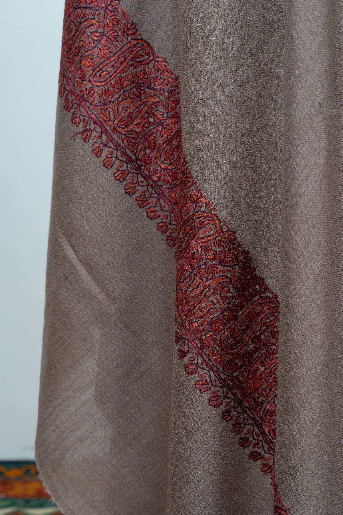 Mocha-brown shawl folds showing a rust paisley border and small leaf edging