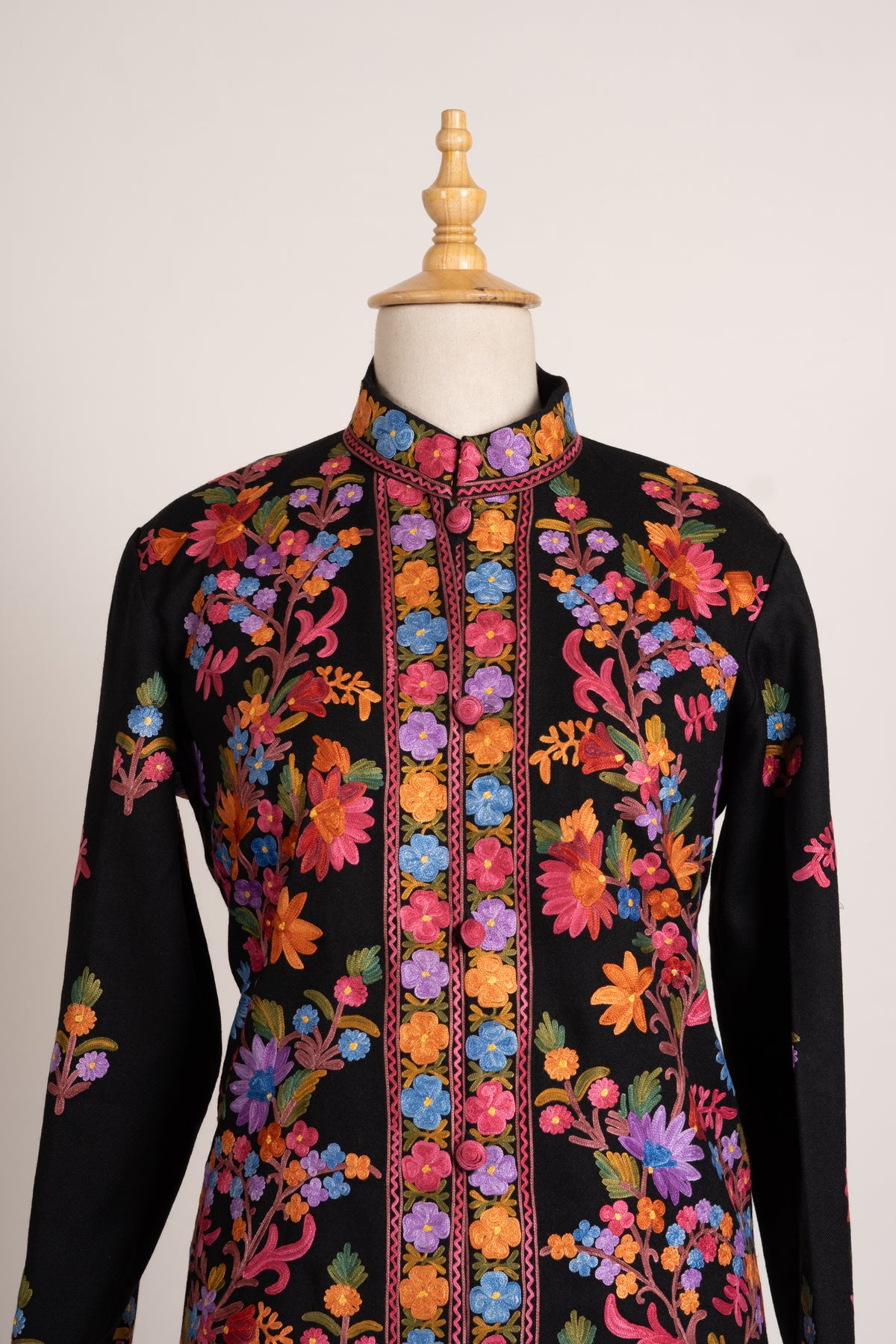 Upper front of the black jacket with a stand collar, bright floral opening borders and multicoloured Aari vines.