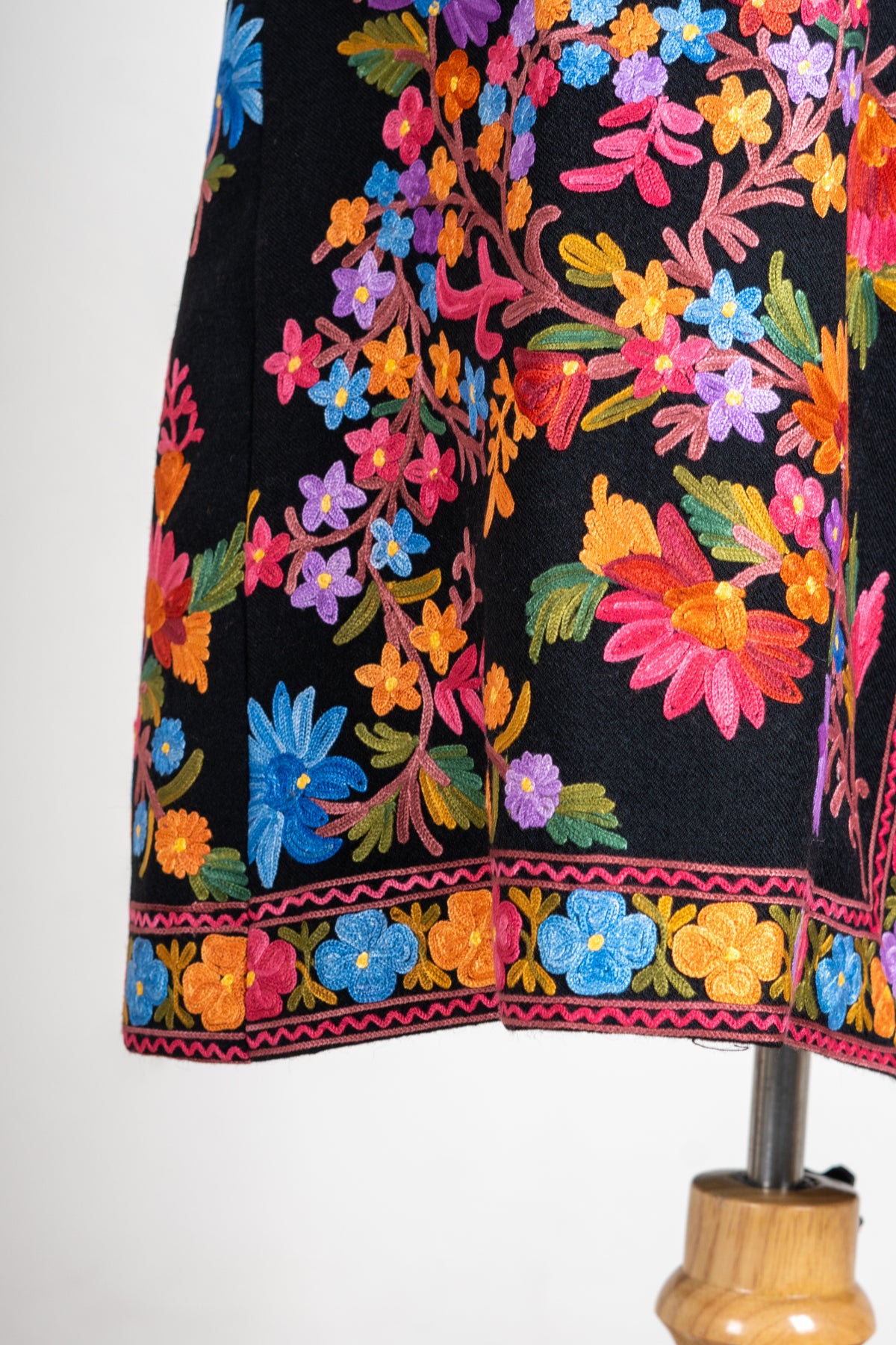Lower side detail of the black jacket with colourful floral vines and a narrow band of flowers along the hem.