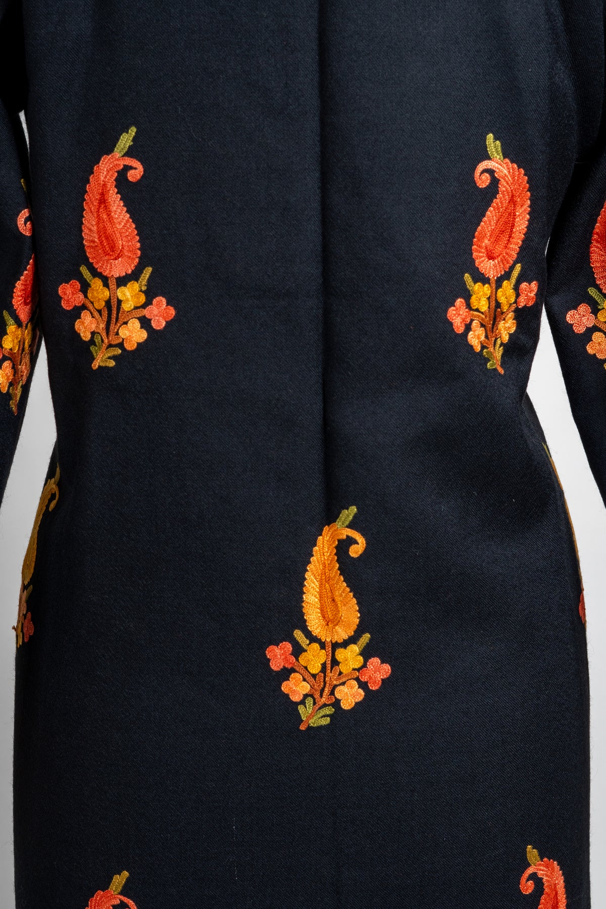 Close back detail of the black jacket with small gold and orange paisleys above tiny flowers