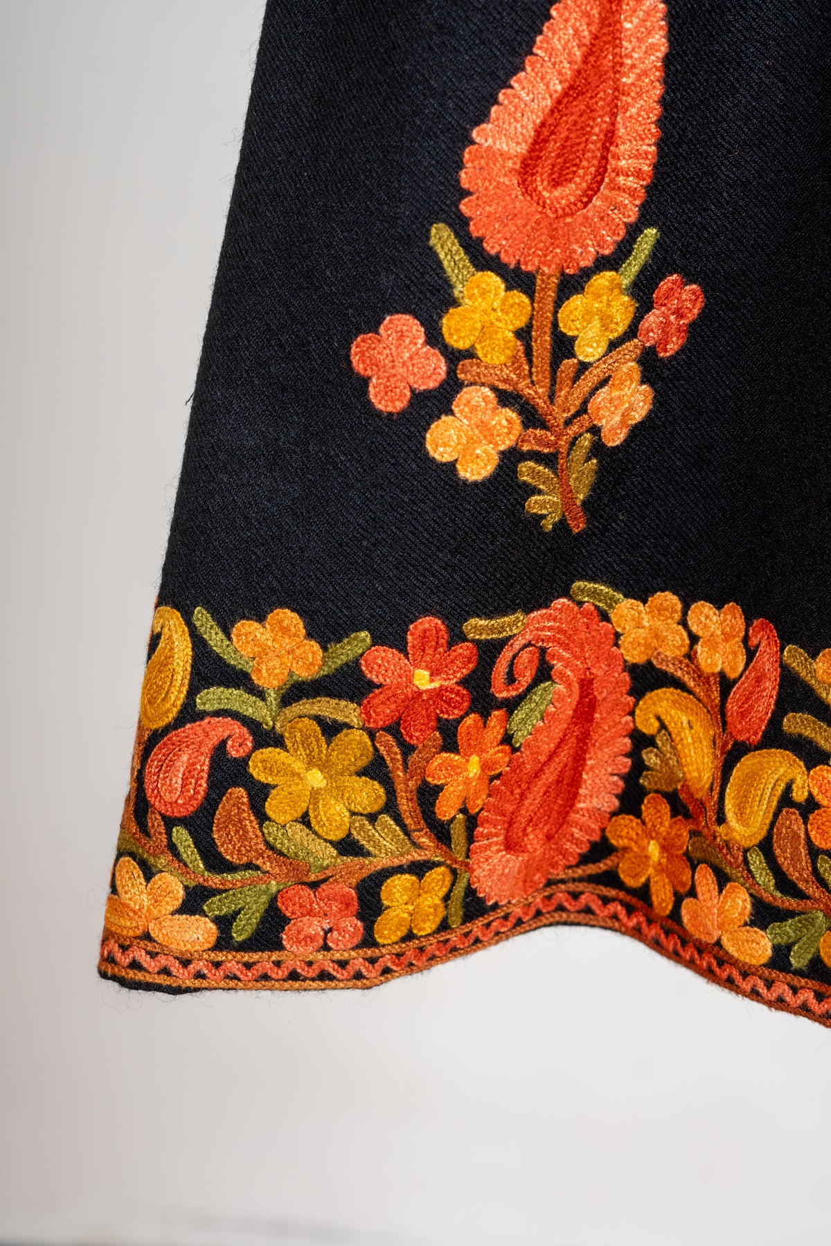 Close-up of an orange paisley sprig above the black jacket’s gold and orange floral hem border