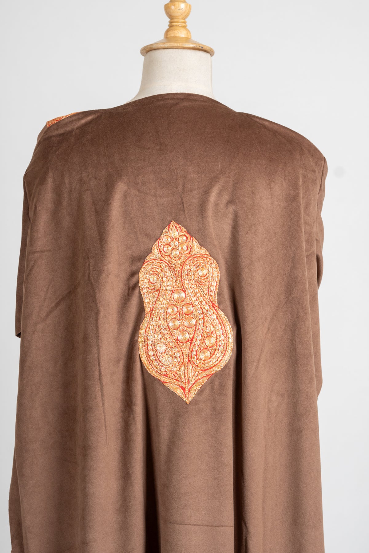 Upper-back view of the brown velvet pheran with a large pointed Tilla motif against the plain fabric.