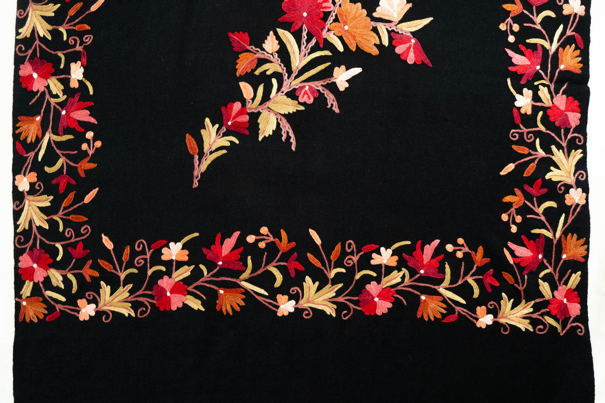 End detail of the black stole with a red-and-gold-toned floral border framing the tip of its central garland.