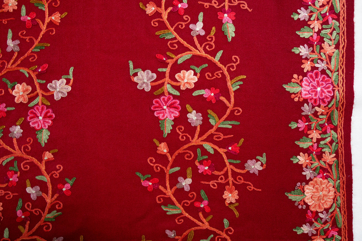 Crimson stole detail with a winding Aari flower vine beside a dense border of pink and coral flowers