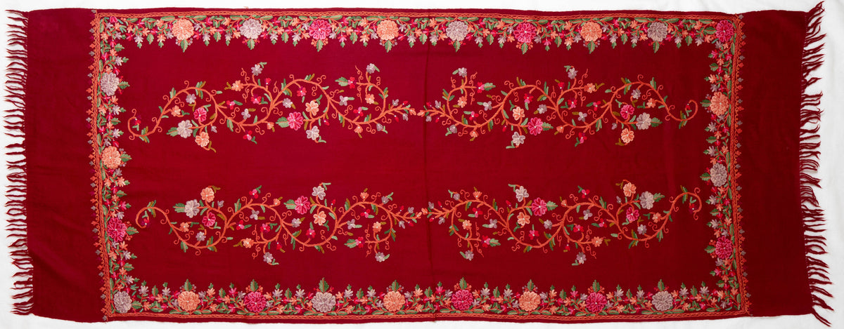 Full crimson Merino wool stole laid flat with two long Aari flower garlands, a matching floral border and red fringed ends