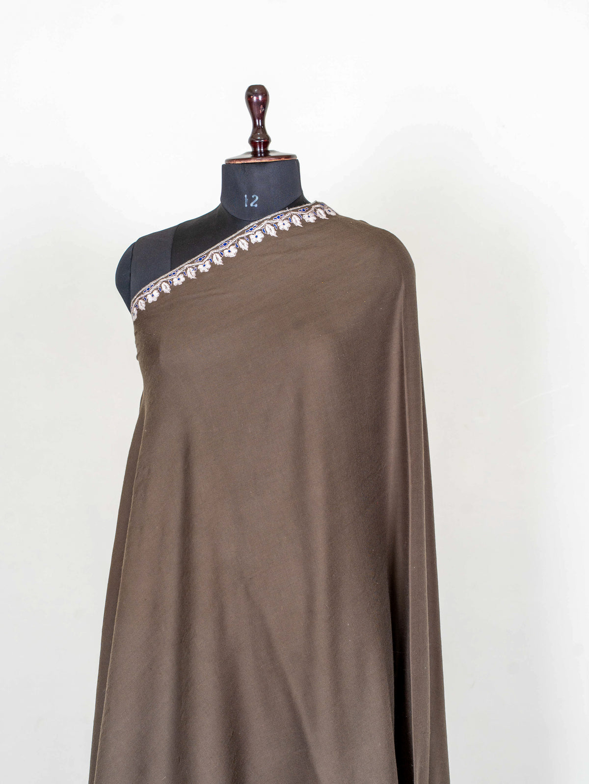 Upper view of the mocha-brown Pashmina shawl, showing its plain body and narrow ivory embroidered shoulder edge
