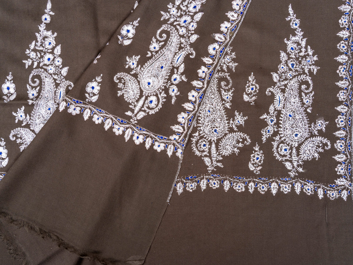 Folded end of the mocha-brown Pashmina shawl, showing overlapping ivory embroidered panels and fine fringe