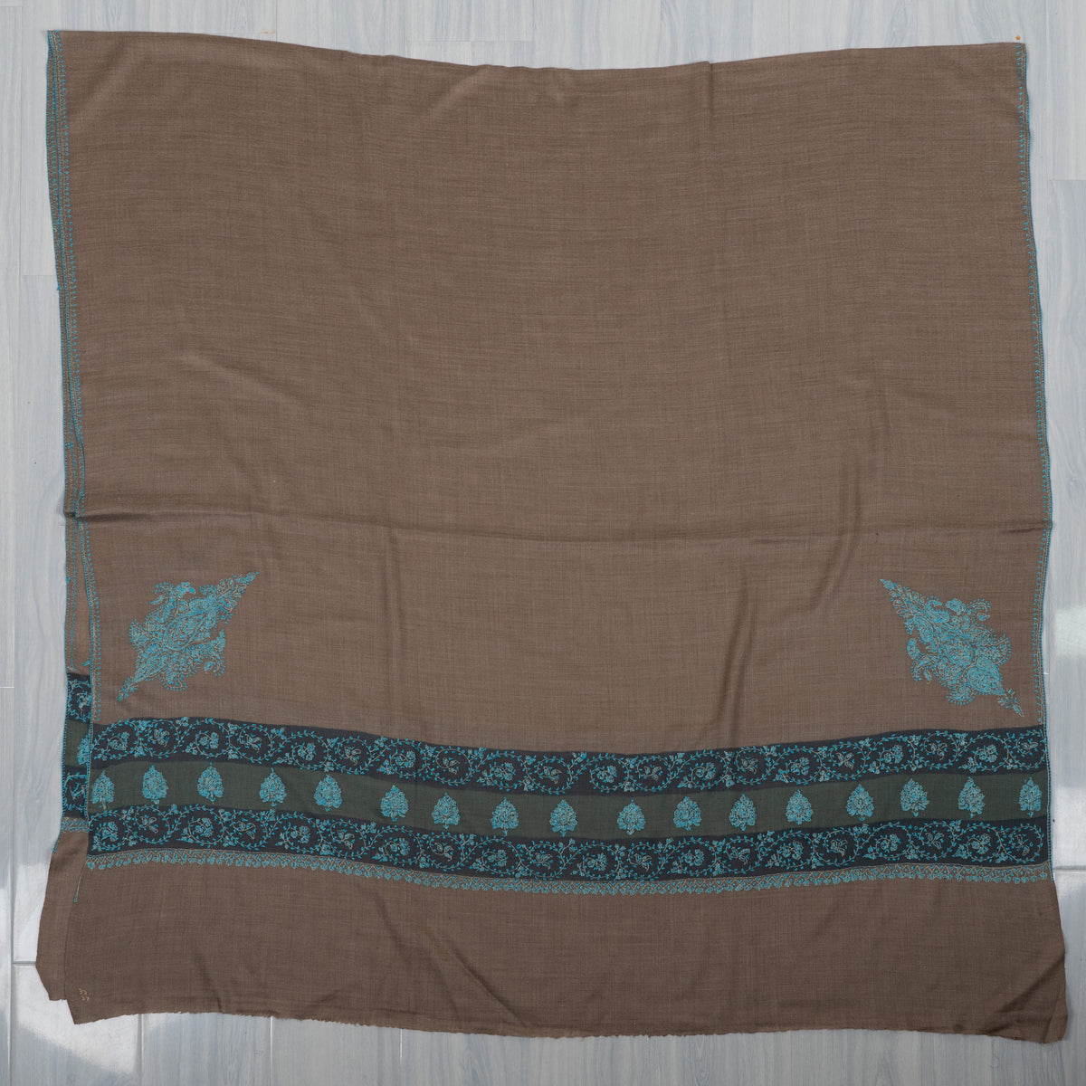 Walnut-brown Merino wool shawl laid flat, with a broad teal embroidered end border and two corner motifs