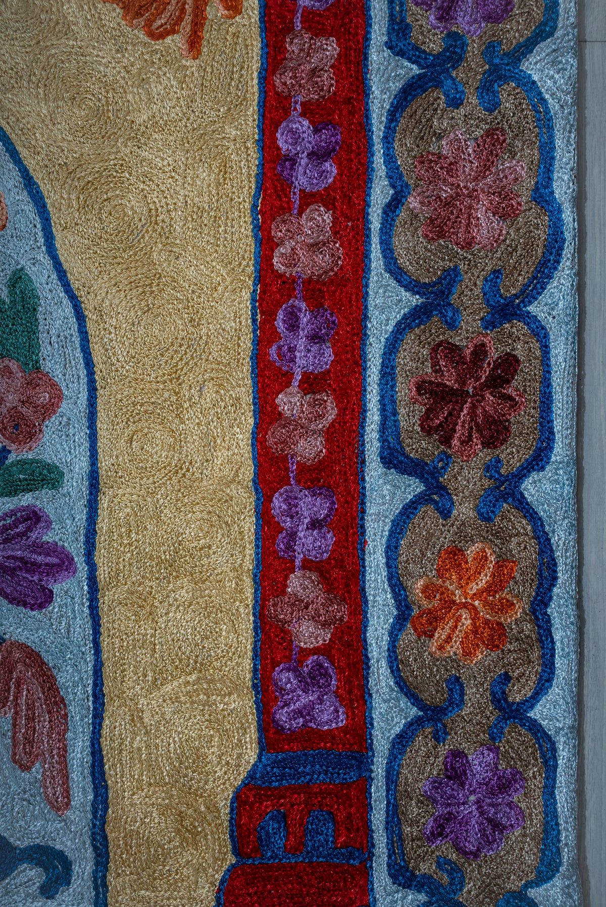 Side detail of the prayer mat with small flowers on red beside a blue-outlined floral border
