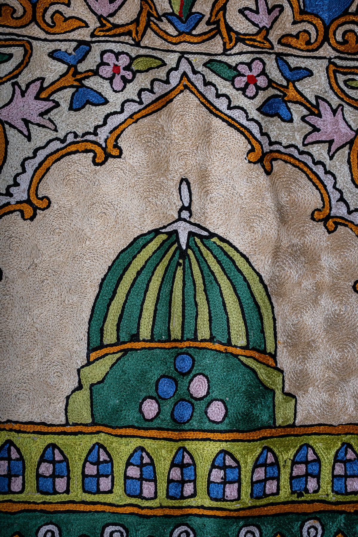 Close-up of the prayer mat's green dome beneath a scalloped arch and embroidered floral surround