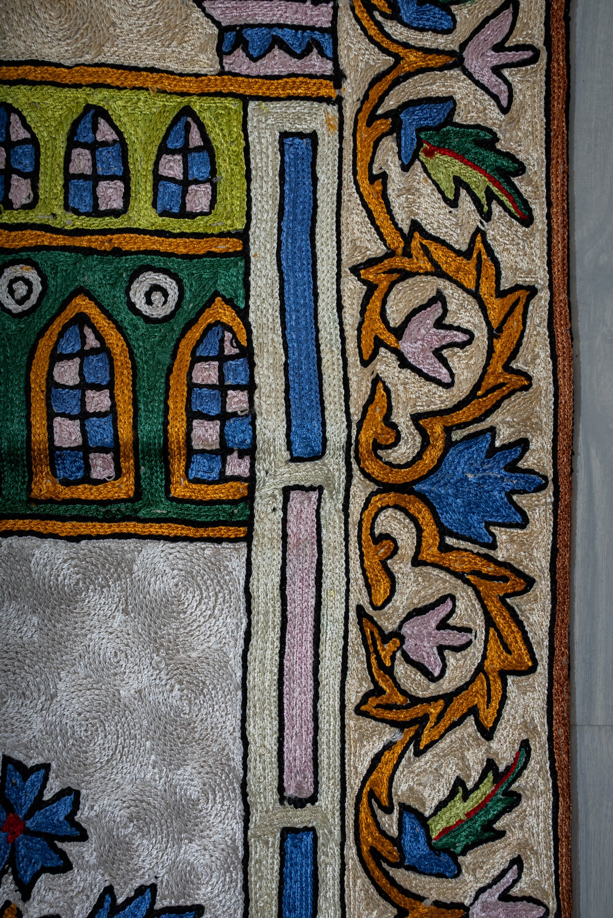 Prayer mat detail showing arched windows beside a colourful embroidered floral border