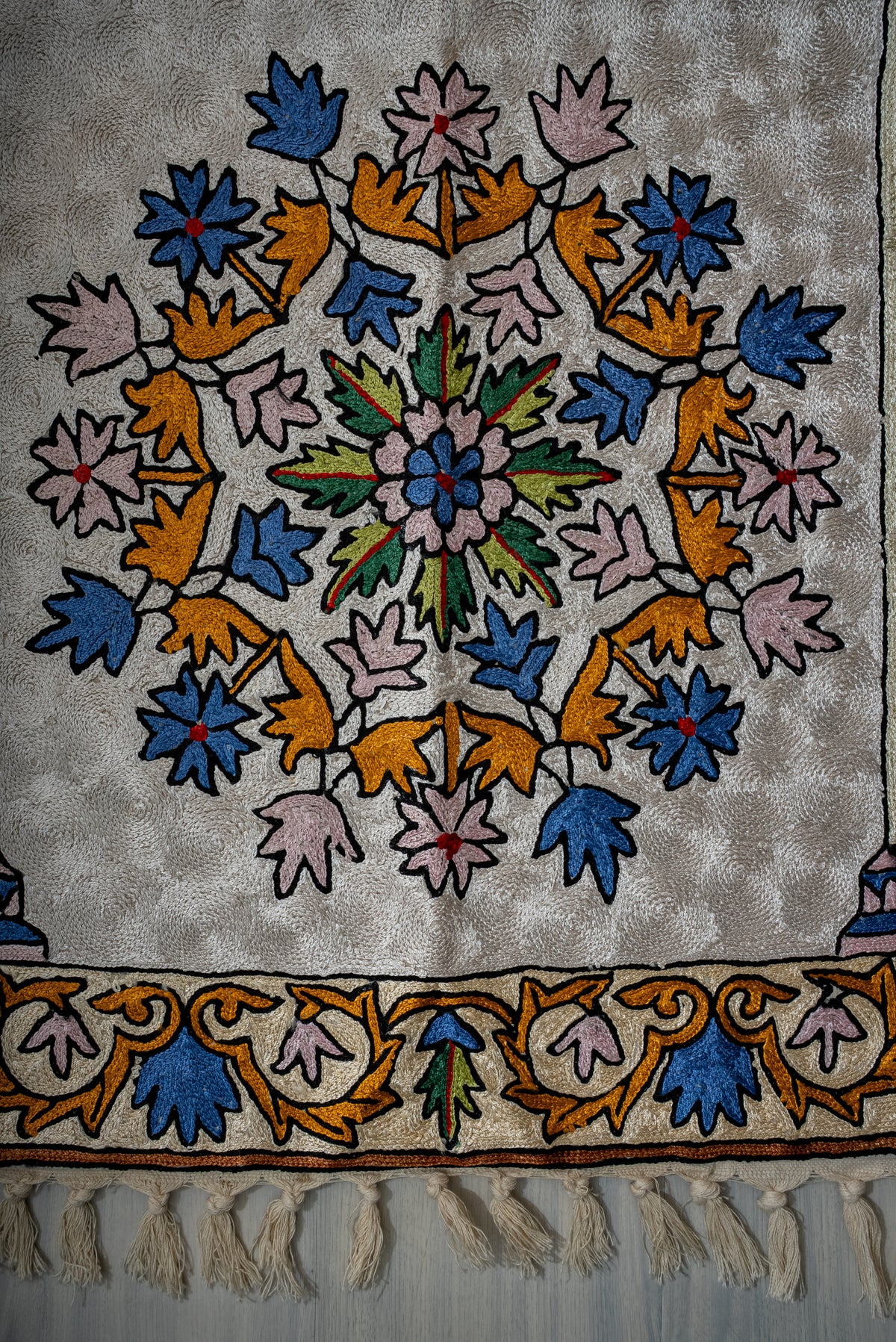 Prayer mat's circular floral medallion above a colourful leafy border and cream tassels