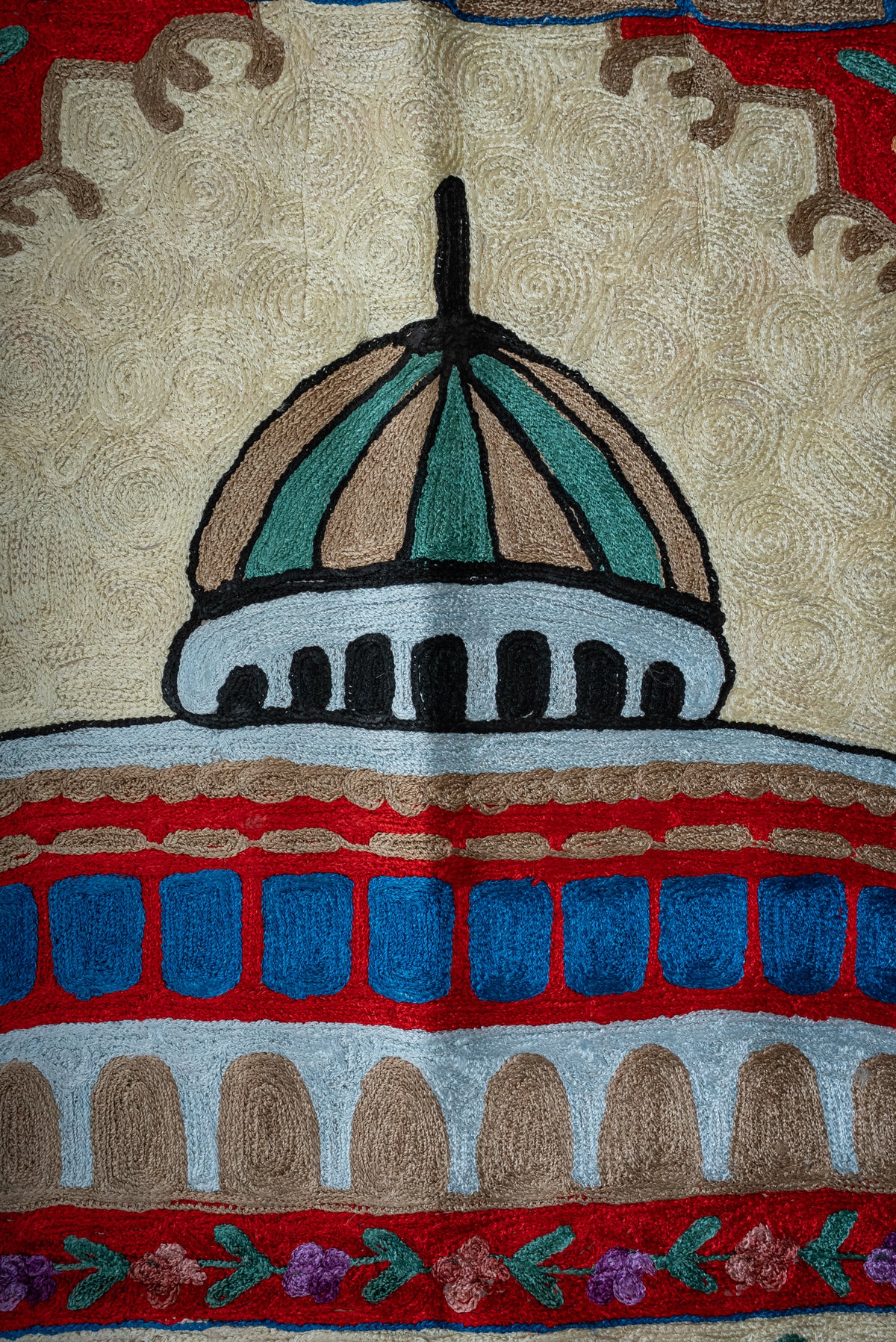 Close-up of the prayer mat's teal and beige dome above blue windows and pale blue architectural arches