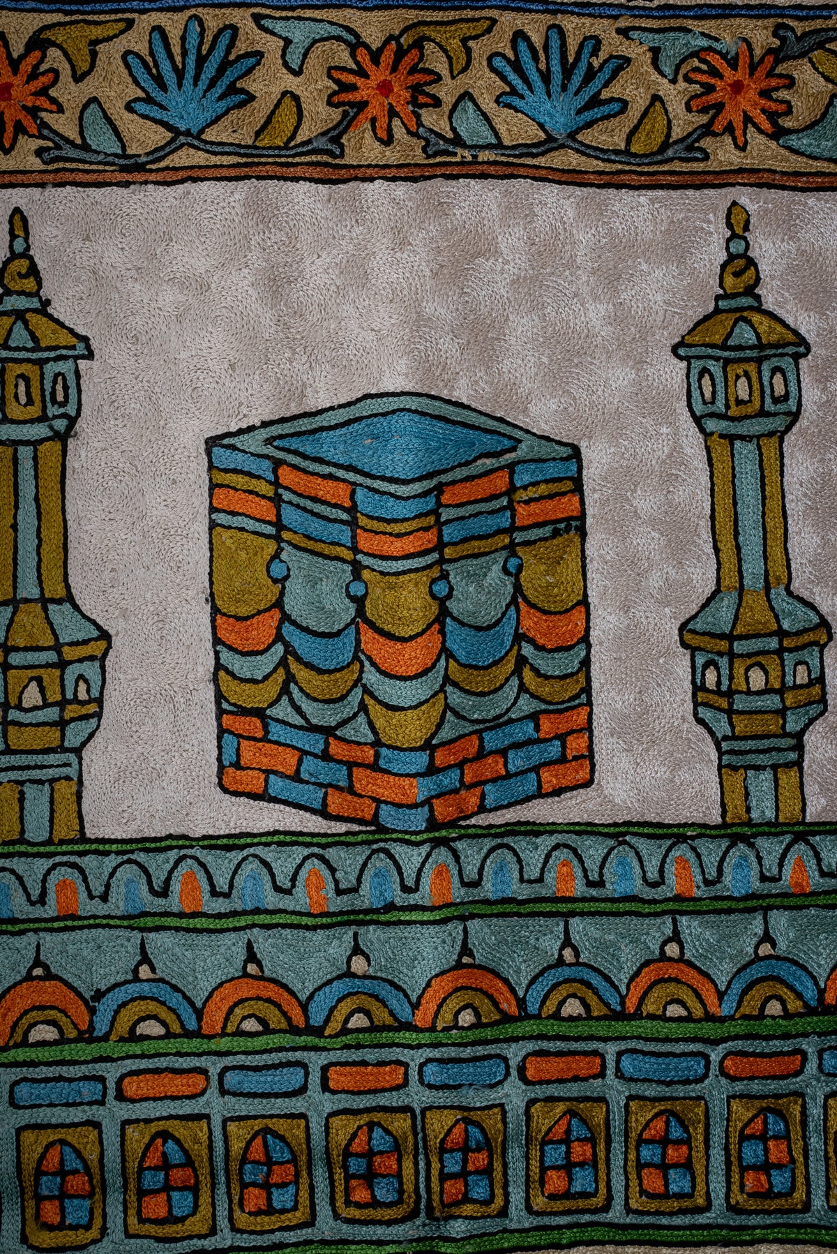 Close-up of the colourful Kaaba motif between two minarets on the embroidered prayer mat