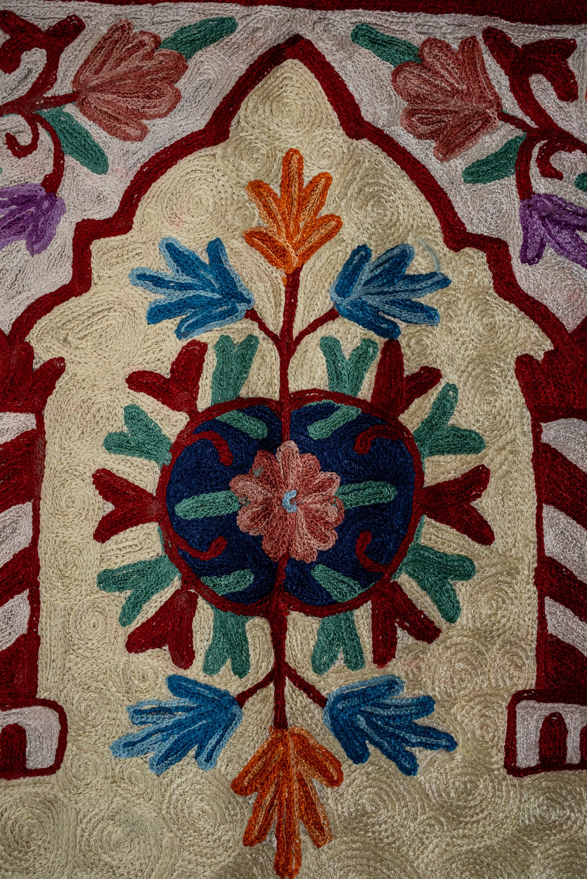Close-up of the prayer mat's blue circular medallion with a pink flower and red, green, blue and orange leaves