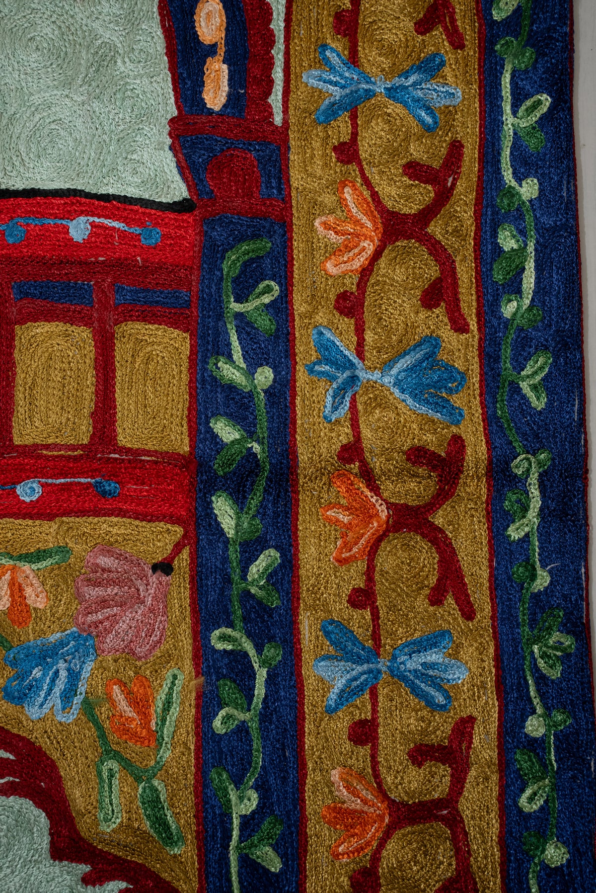 Side detail of the prayer mat's gold floral border framed by navy bands with green leafy vines