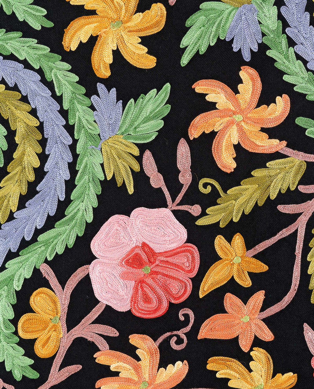 Close-up of pink, orange and yellow embroidered flowers beside curling green and lavender leaves on black fabric.