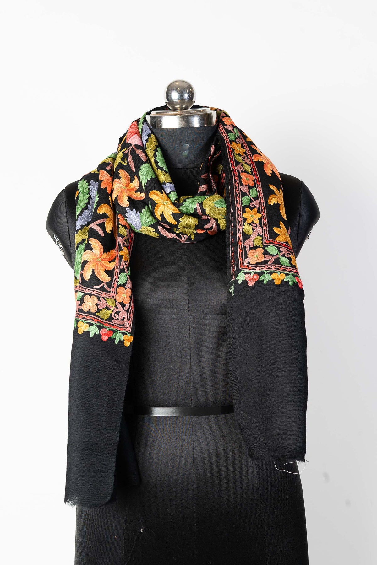Black stole looped around a mannequin’s neck, with colourful embroidered borders above two long plain black ends.