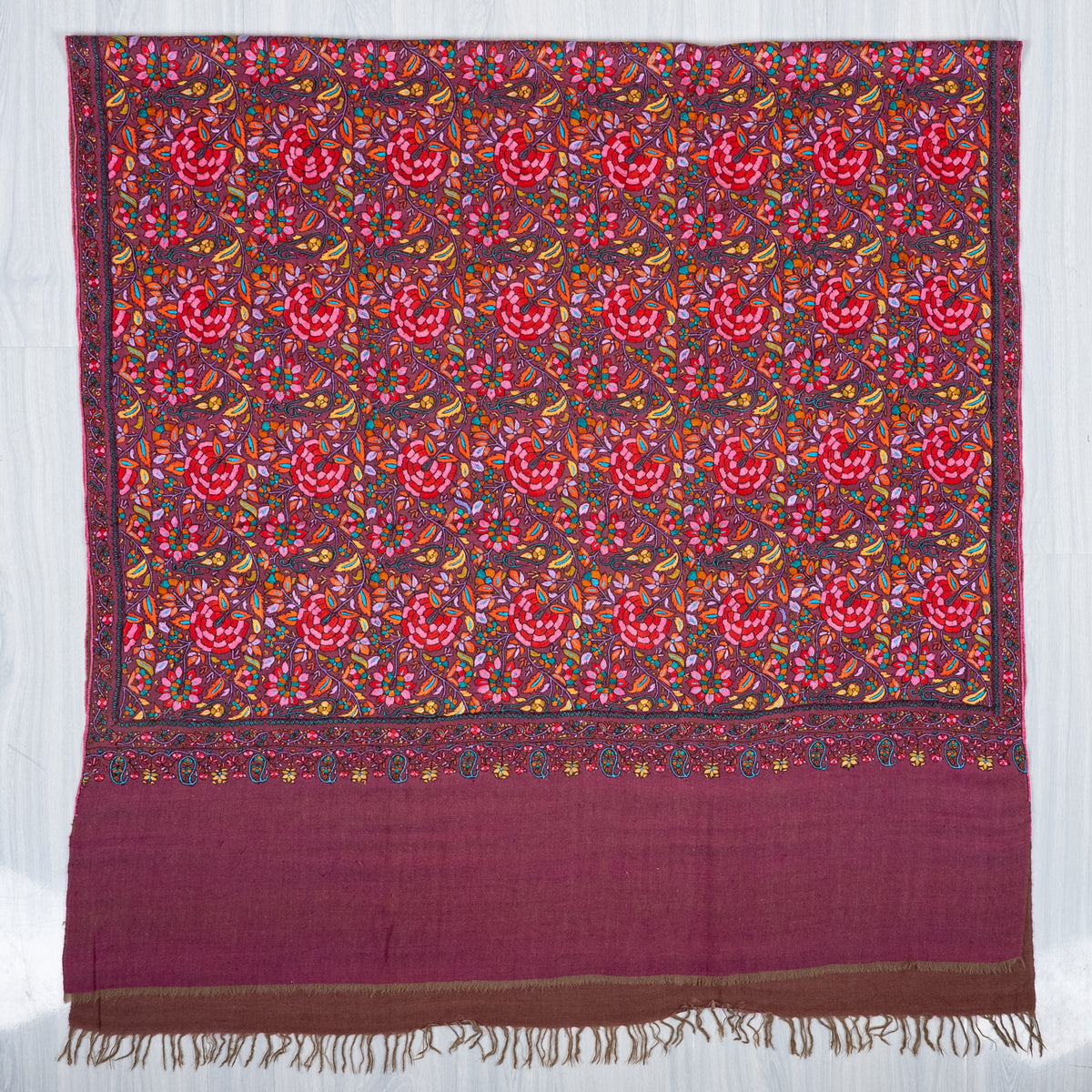 Plum Pashmina shawl laid flat, with a dense multicoloured floral panel, narrow ornate borders and a broad plain fringed end