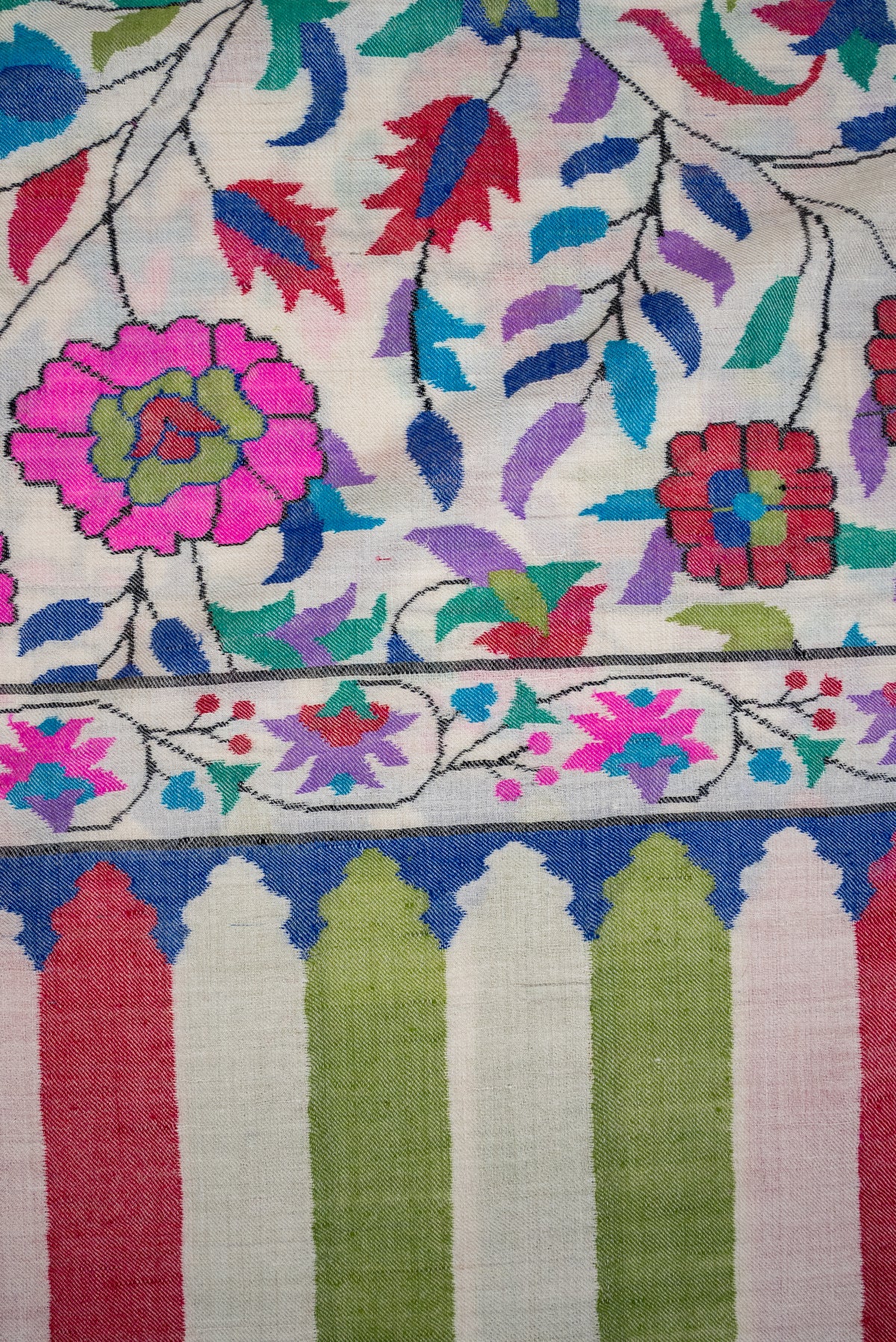 Close-up of bright pink flowers and colourful leaves above the flower border and striped end of an ivory Pashmina shawl