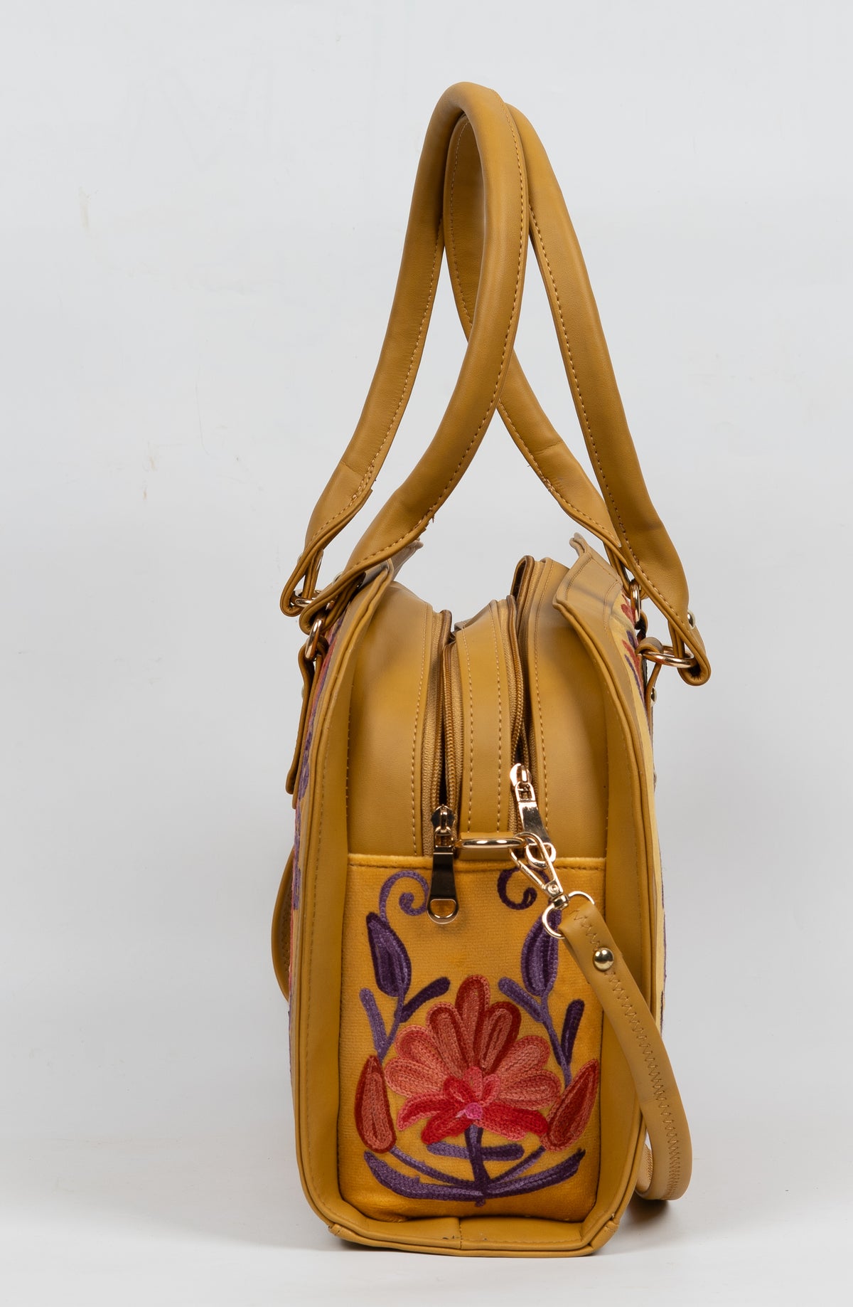 Side view of the mustard bag showing its floral end pocket, top zippers and handles.