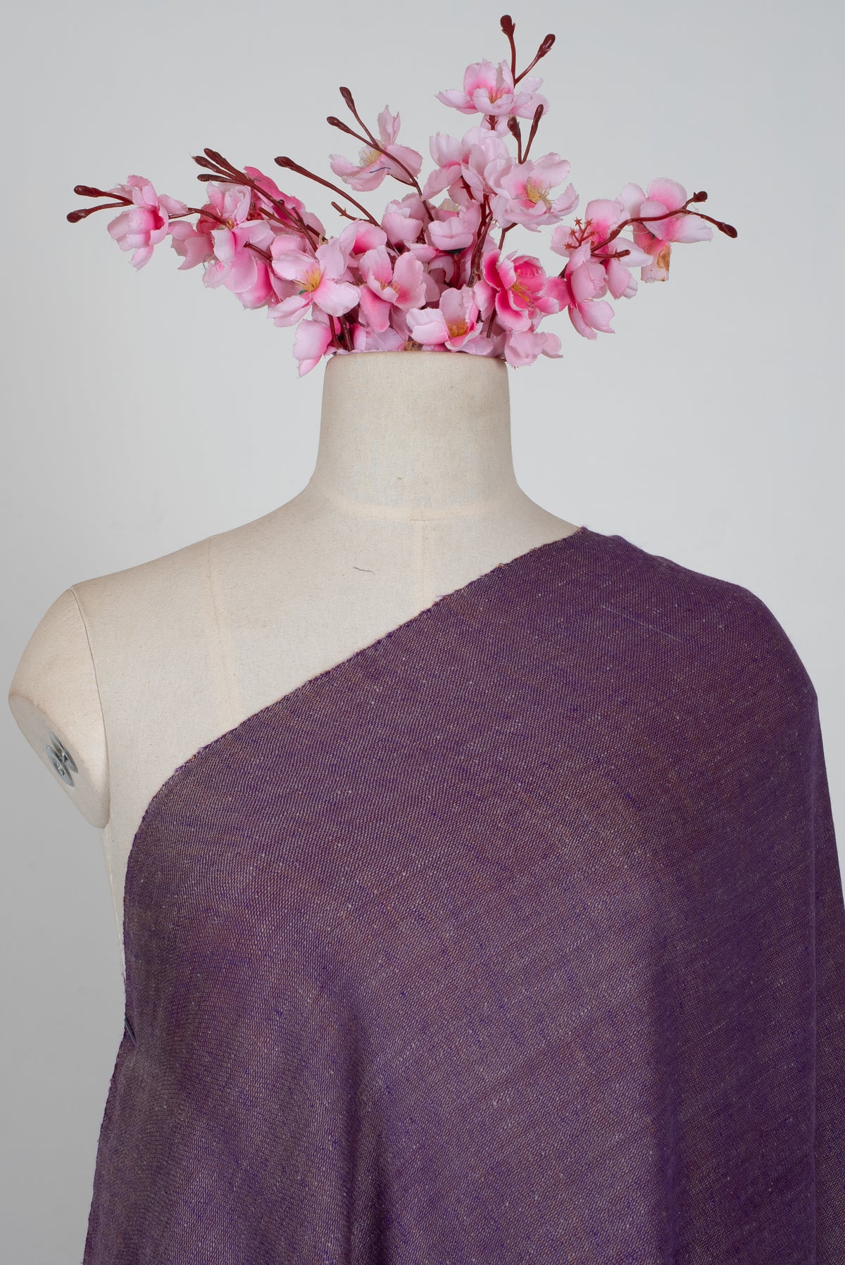 Upper view of a plain muted-purple Pashmina shawl draped diagonally across a mannequin, showing its fine texture.
