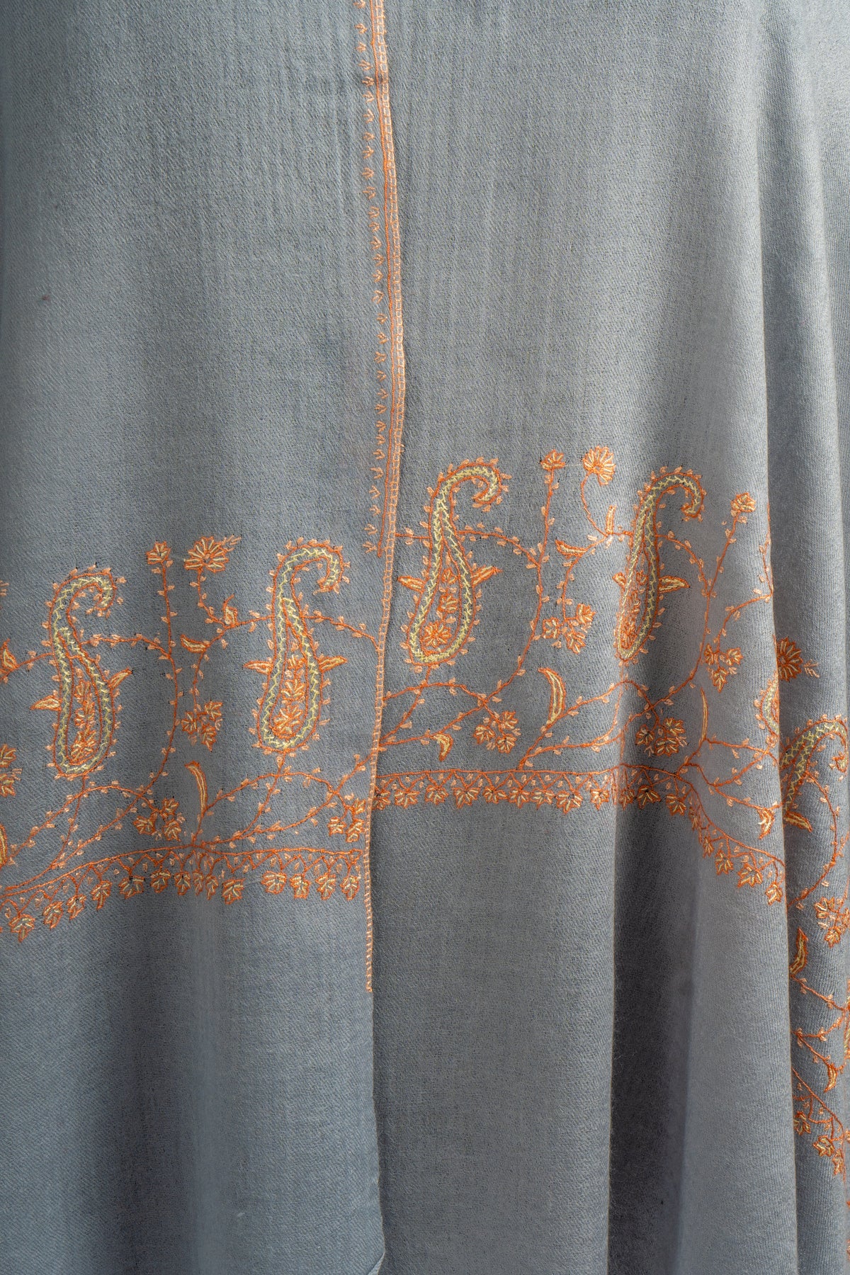 Front drape detail of the grey stole with orange paisley embroidery across both hanging ends.