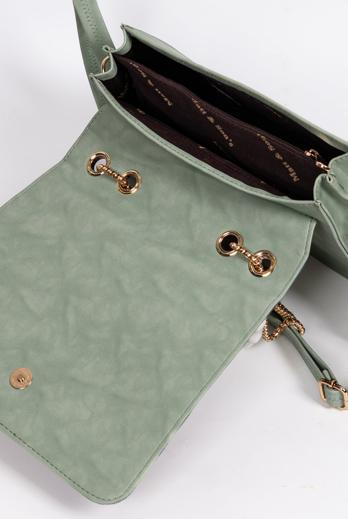 Open teal chain bag showing the pale green underside of the flap, gold-toned fastener and dark zippered interior