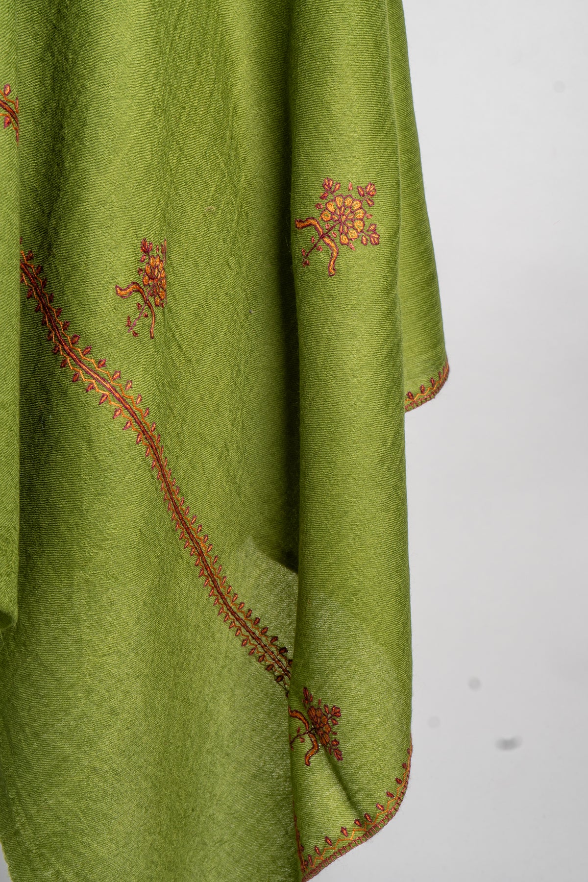 Hanging corner of a green stole with small red and orange Sozni flowers and a narrow embroidered leaf border