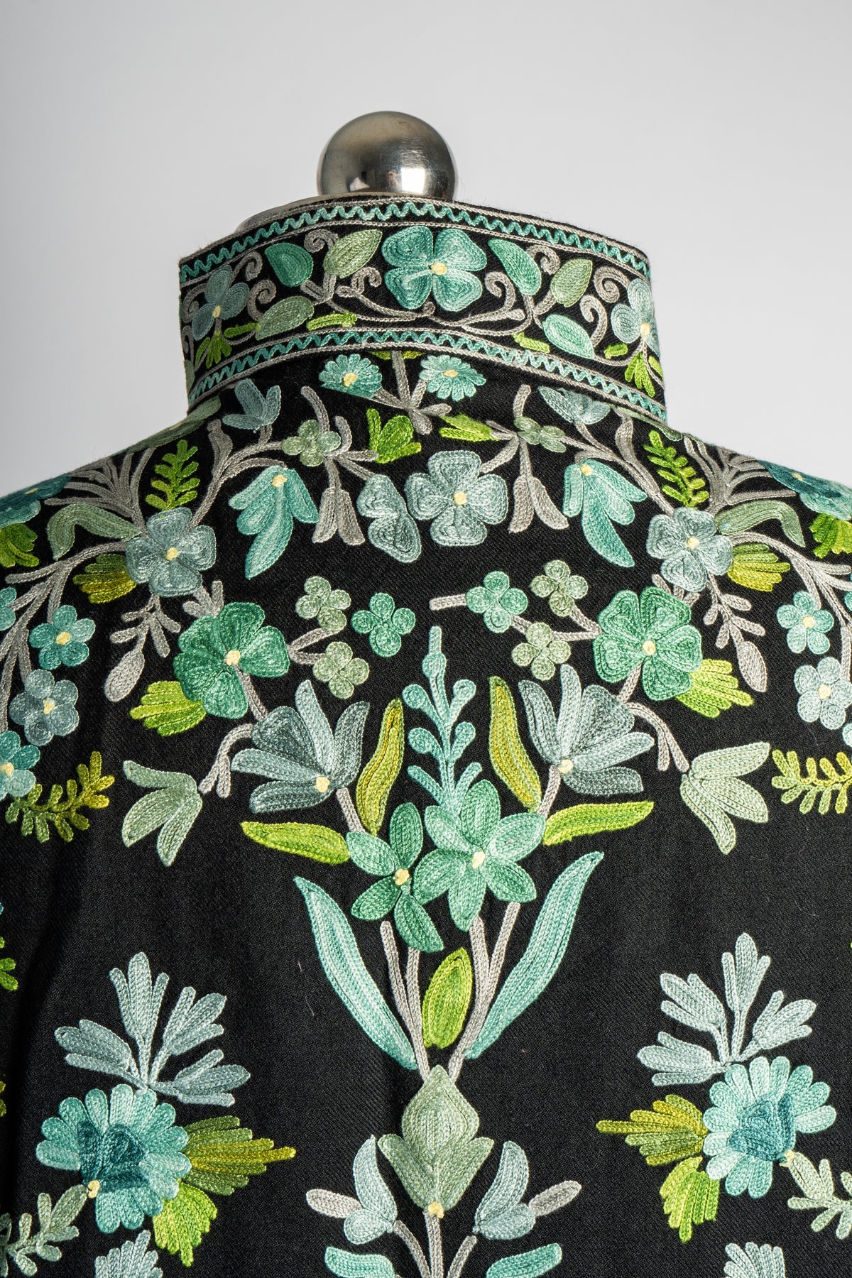 Rear collar and shoulder detail of the black jacket, with mint floral embroidery and an ornate standing collar.
