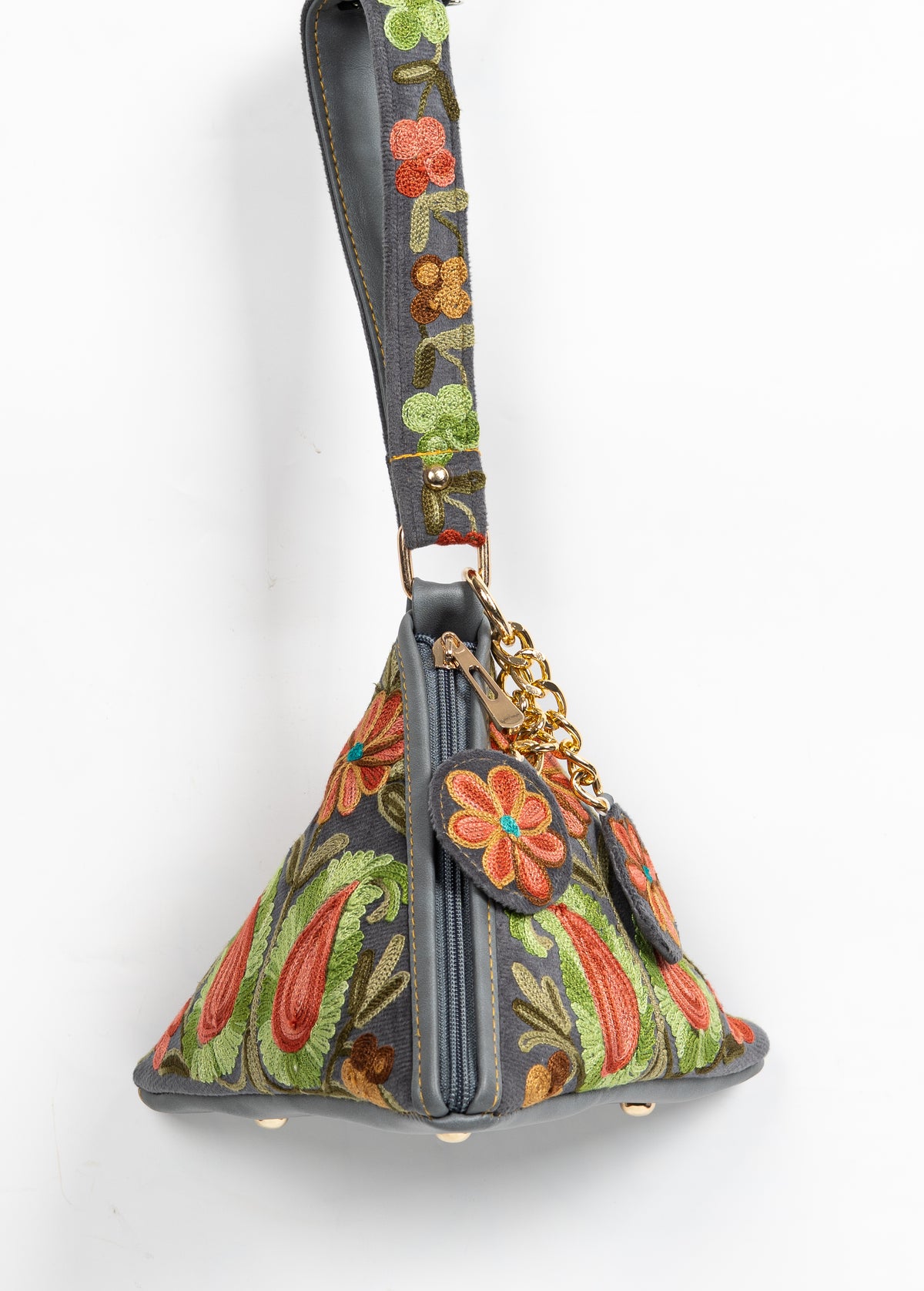 Charcoal pyramid bag hanging from an embroidered shoulder strap, with coral-and-green paisleys and a zip down the front edge
