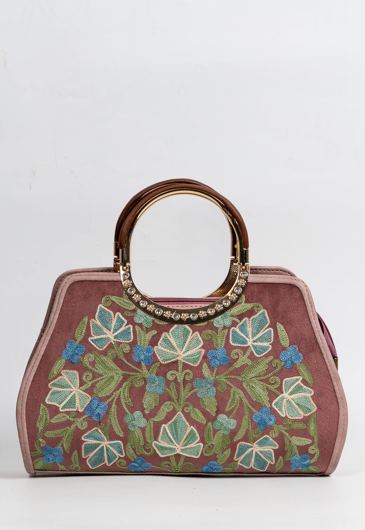 Front view of a mauve handbag with white-outlined green leaves, blue flowers and rounded gold-toned handles with bright decorative accents