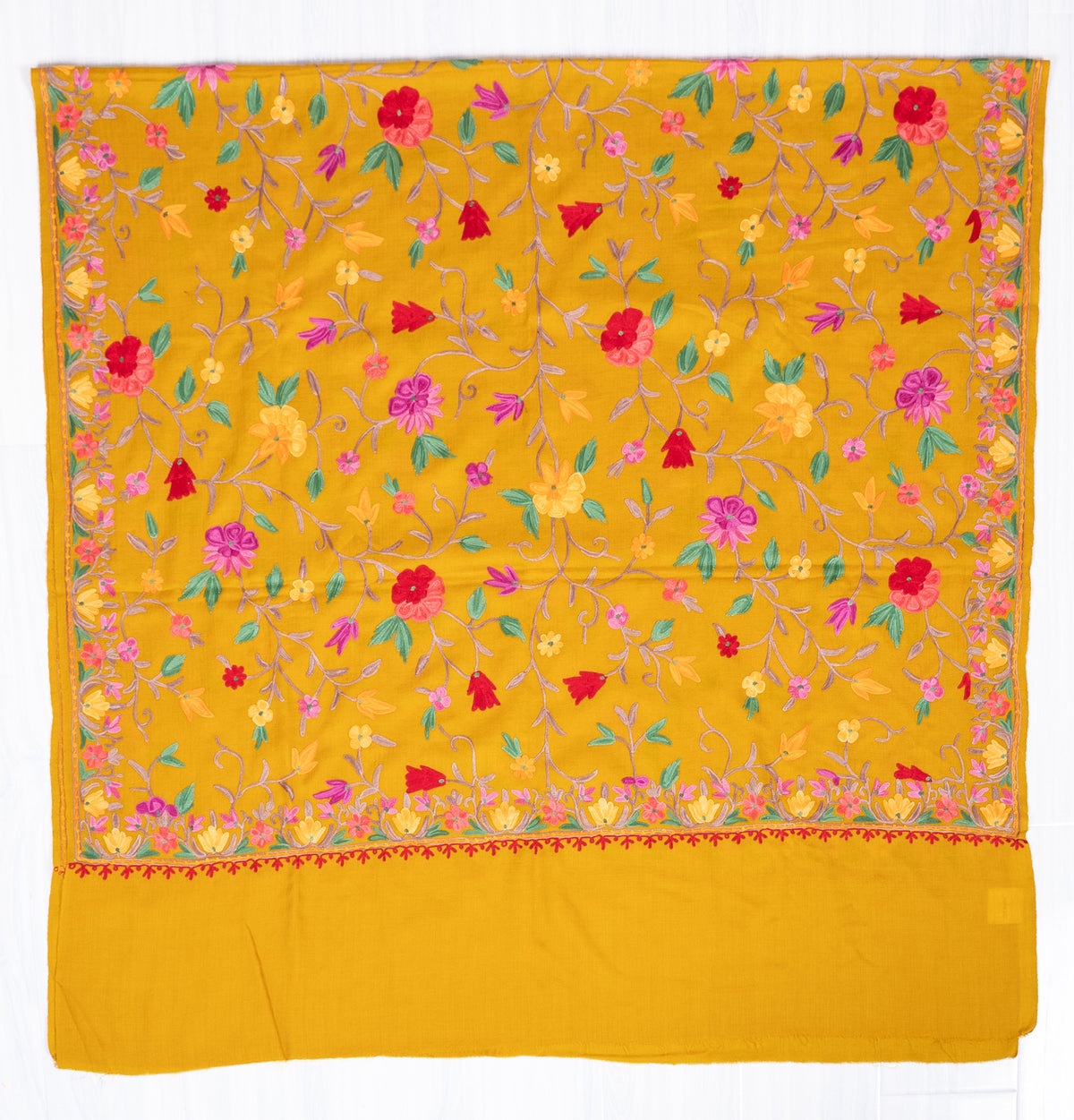 Mustard shawl spread flat, with colourful floral Aari vines, narrow embroidered borders and a wide plain end