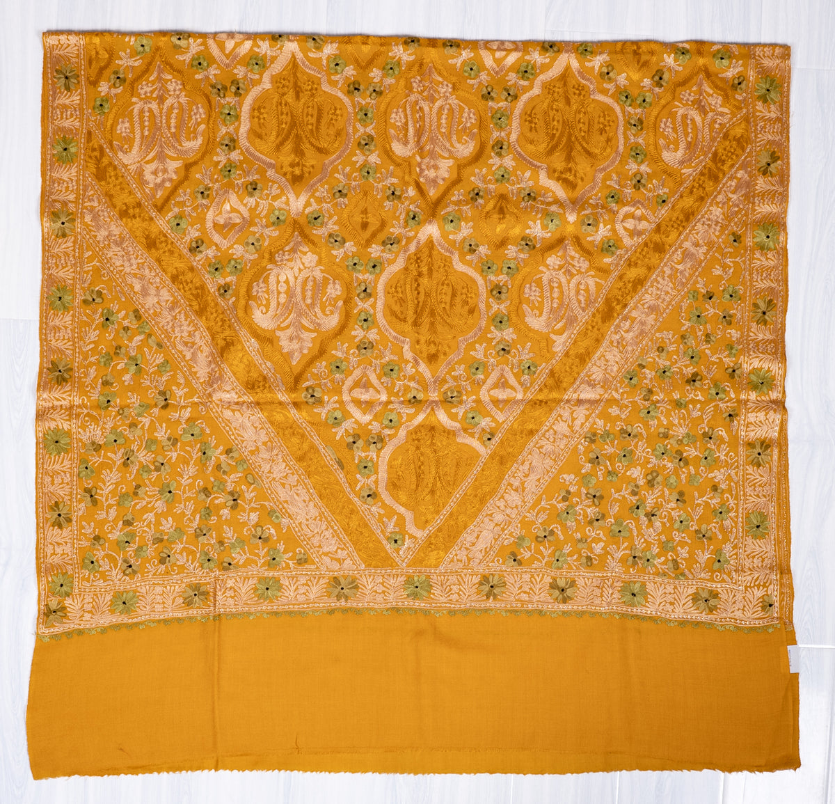 Mustard shawl spread flat, with a V-shaped Aari medallion panel, olive-green floral accents and a broad plain end