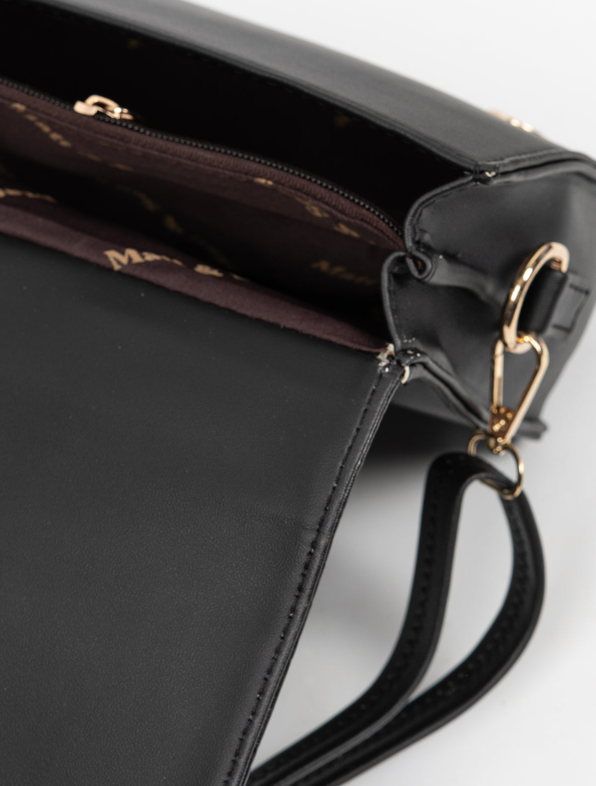 Close-up inside the open black handbag, with a zipped central section, brown lining and a gold-toned shoulder-strap clip