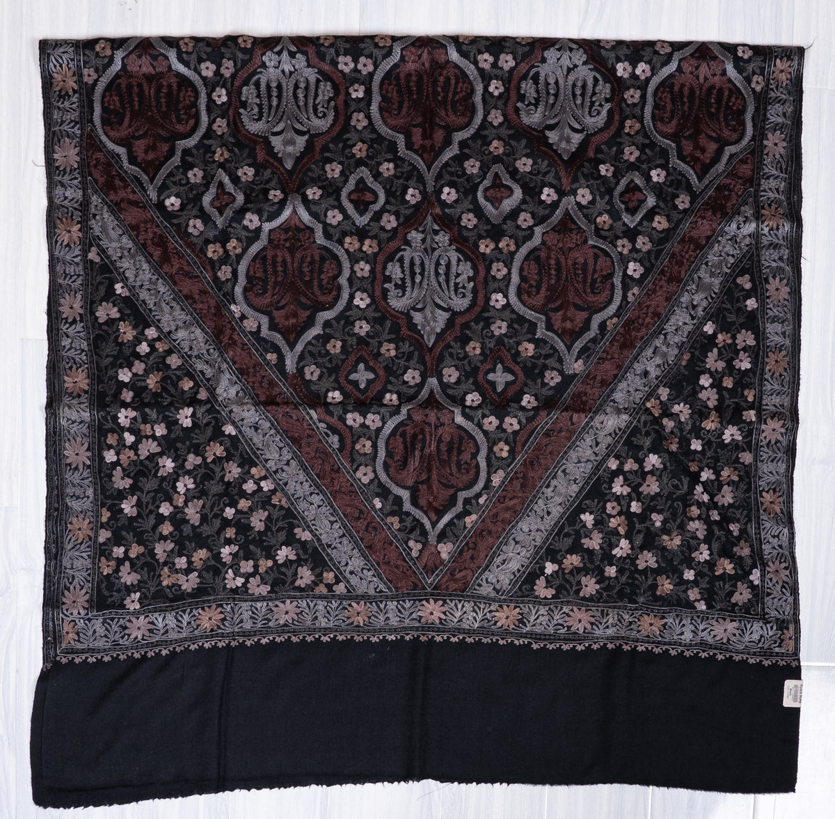 Black shawl spread flat, showing a triangular paisley panel, small floral sides and a plain black end
