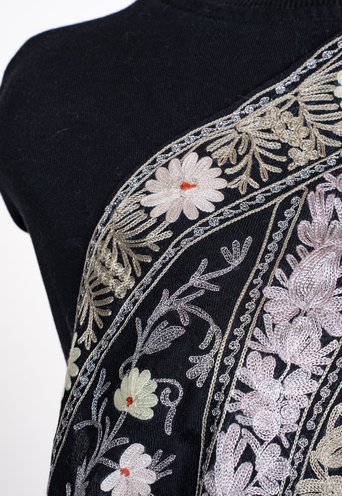 Shoulder close-up of the black shawl, with pale Aari flowers, leafy bands and small red flower centres