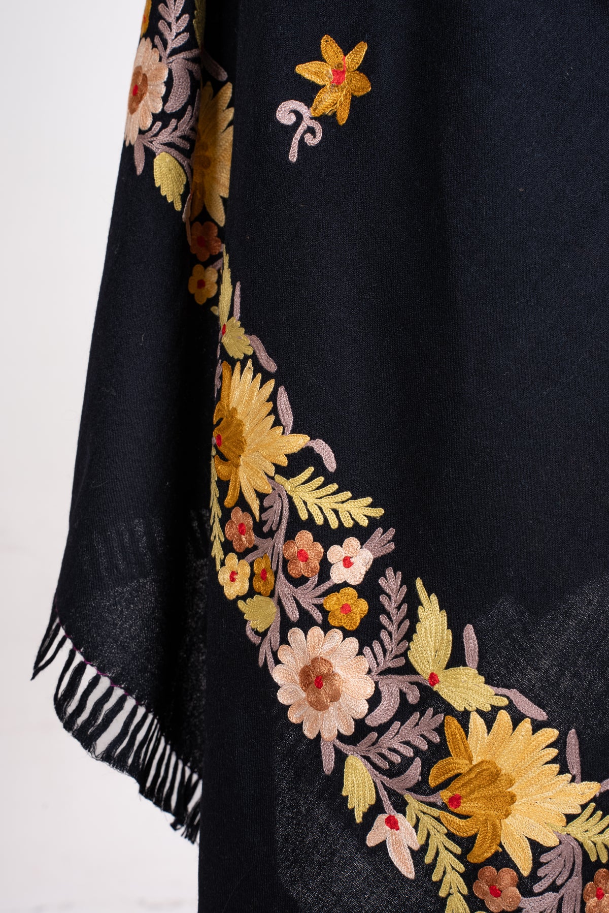 Lower draped detail of the black shawl, showing cream and yellow Aari flowers above black fringe